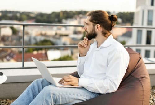 Man working on laptop outdoors on a rooftop terrace